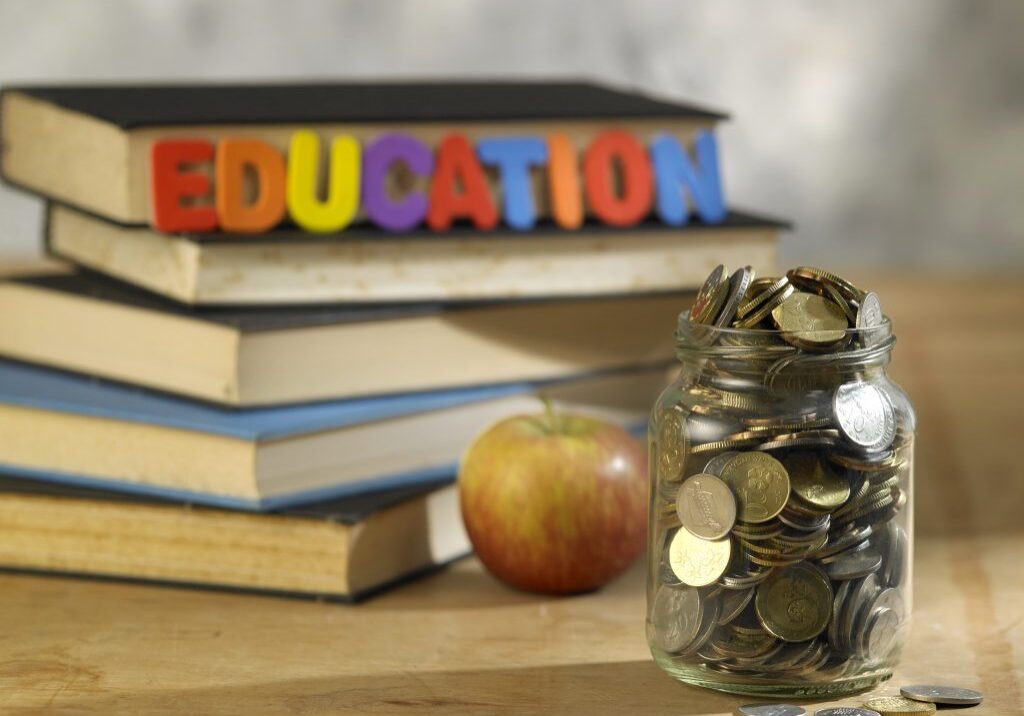 saving jar with coins on top of books